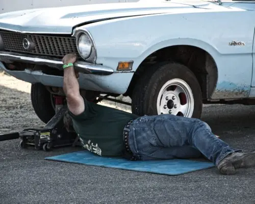 mechanic working on engine from under car