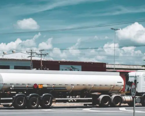 Tanker truck in front of businesses on a sunny day