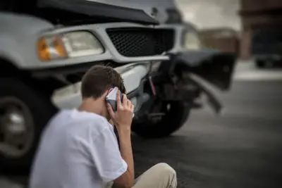 young man on phone after car accident