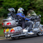 A motorcycle with a driver and a passenger rides along a road, both wearing helmets and protective gear, illustrating a scenario where an injured motorcycle passenger in Colorado Springs may need separate legal representation after an accident.