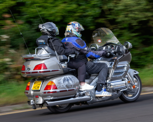 A motorcycle with a driver and a passenger rides along a road, both wearing helmets and protective gear, illustrating a scenario where an injured motorcycle passenger in Colorado Springs may need separate legal representation after an accident.