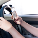 Driver holding a smartphone while driving, illustrating distracted driving and texting while driving as key evidence in a fatal crash investigation in Colorado Springs