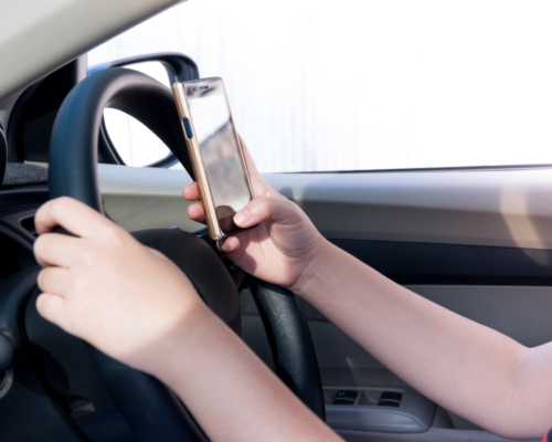 Driver holding a smartphone while driving, illustrating distracted driving and texting while driving as key evidence in a fatal crash investigation in Colorado Springs