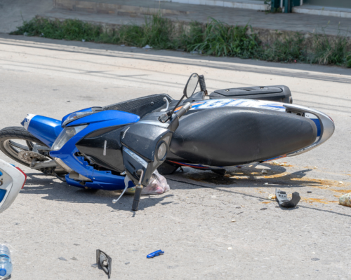 A crashed motorcycle lying on the roadway surrounded by debris, illustrating the severe impact of motorcycle accidents and the serious injuries riders often suffer.
