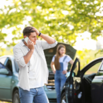 Man on phone at car accident scene with visible vehicle damage, illustrating communication risks with insurance adjusters after a Woodland Park car accident and the importance of legal representation.