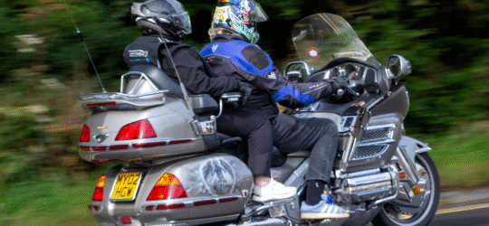 A motorcycle with a driver and a passenger rides along a road, both wearing helmets and protective gear, illustrating a scenario where an injured motorcycle passenger in Colorado Springs may need separate legal representation after an accident.