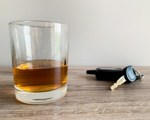 A glass of whiskey on a table next to a car key