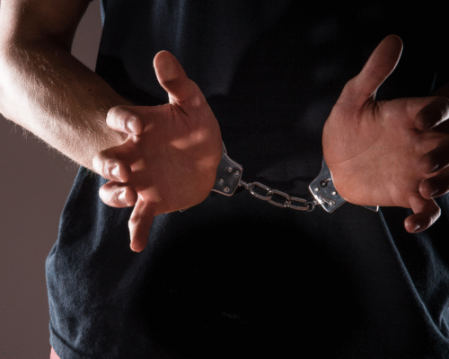A man from the chest down in handcuffs holding his hands in front of him.