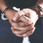 Close-up of a person's hands clasped together and handcuffed, representing the urgent need to hire a criminal defense lawyer Colorado Springs.