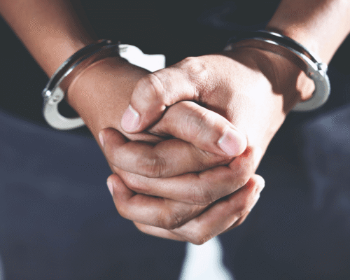 Close-up of a person's hands clasped together and handcuffed, representing the urgent need to hire a criminal defense lawyer Colorado Springs.