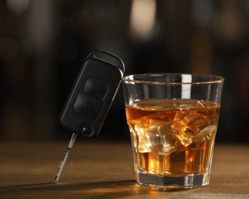 Alcohol drink next to car keys, illustrating the high-stakes risk of DUI while parked and the application of Colorado DUI laws.
