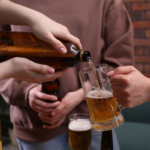 Hands pouring beer into a glass from a bottle while others hold drinks nearby, illustrating alcohol service scenarios relevant to dram shop and social host liability laws in Colorado Springs.