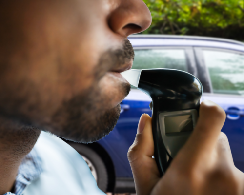 Close-up of a driver taking a breathalyzer test during a roadside stop, illustrating DUI testing procedures and legal considerations in Black Forest, Colorado.