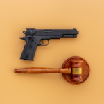 A handgun and judge’s gavel placed side by side, symbolizing the legal consequences of firearm possession in domestic violence cases and the intersection of criminal law and gun rights.