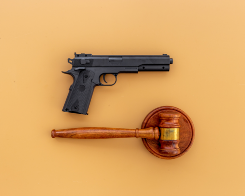 A handgun and judge’s gavel placed side by side, symbolizing the legal consequences of firearm possession in domestic violence cases and the intersection of criminal law and gun rights.
