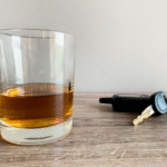 A glass of whiskey on a table next to a car key