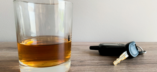 A glass of whiskey on a table next to a car key