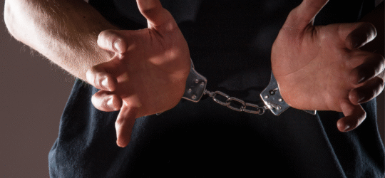 A man from the chest down in handcuffs holding his hands in front of him.