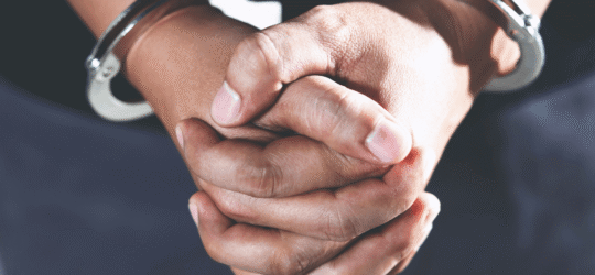 Close-up of a person's hands clasped together and handcuffed, representing the urgent need to hire a criminal defense lawyer Colorado Springs.
