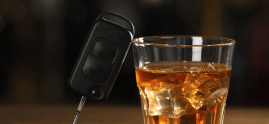 Alcohol drink next to car keys, illustrating the high-stakes risk of DUI while parked and the application of Colorado DUI laws.