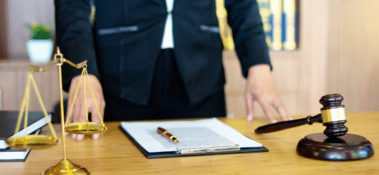 A lawyer in a suit from the chest down standing over a desk with paperwork and legal paraphernalia