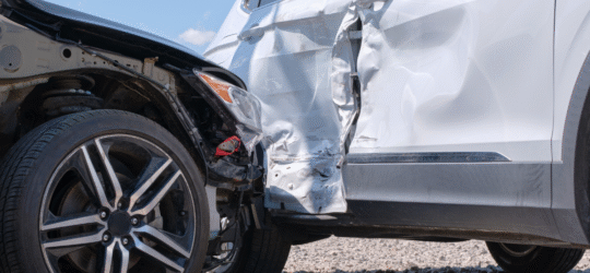 A side on collision between a white and black car.