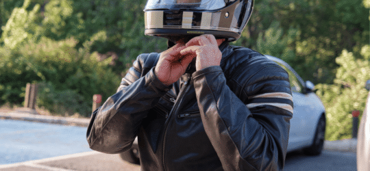 Motorcyclist putting on helmet in parking lot
